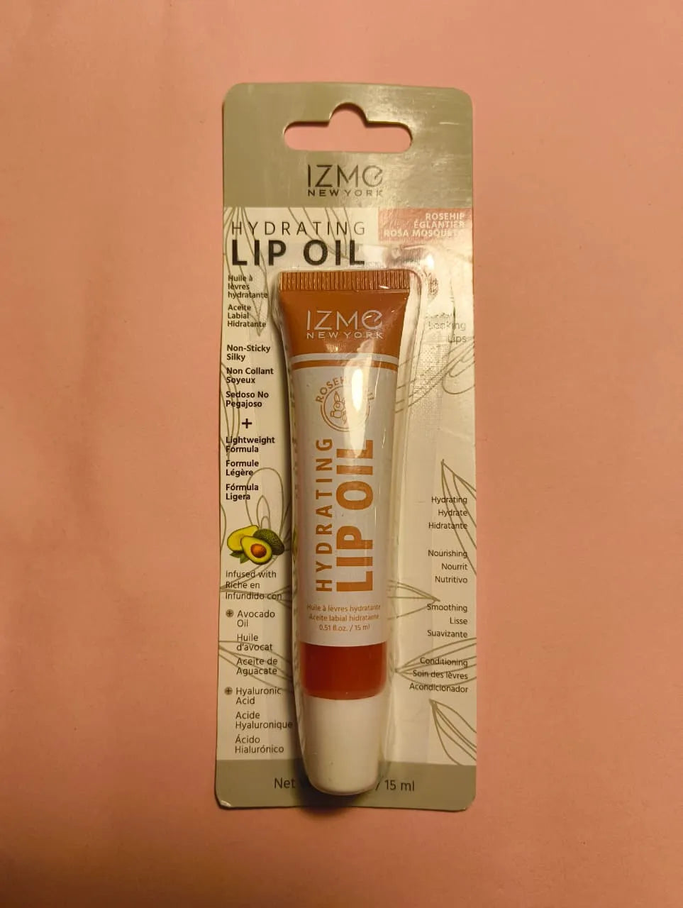 IZMO Hydrating Lip OIl in a sleek tube packaging on a pink background showcasing its hydrating benefits.