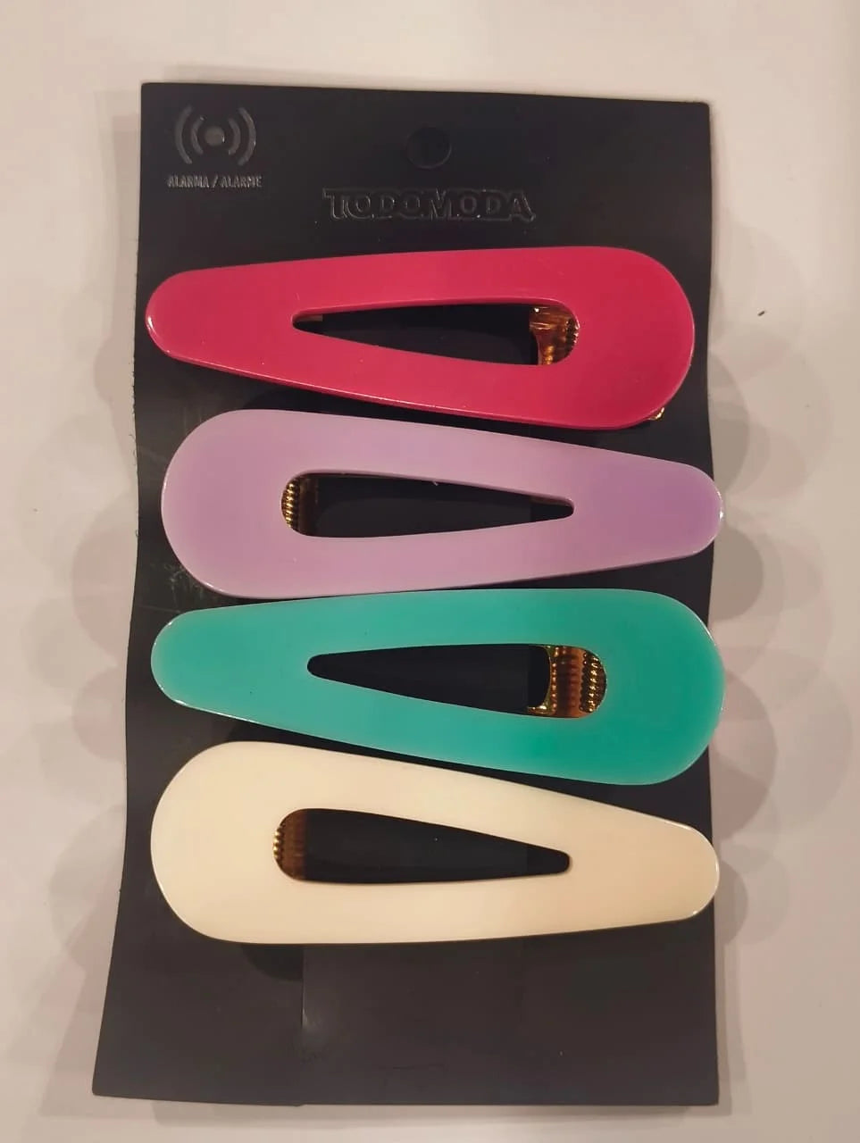 Set of colorful hair clips on a black card with 'Todomoda' branding.