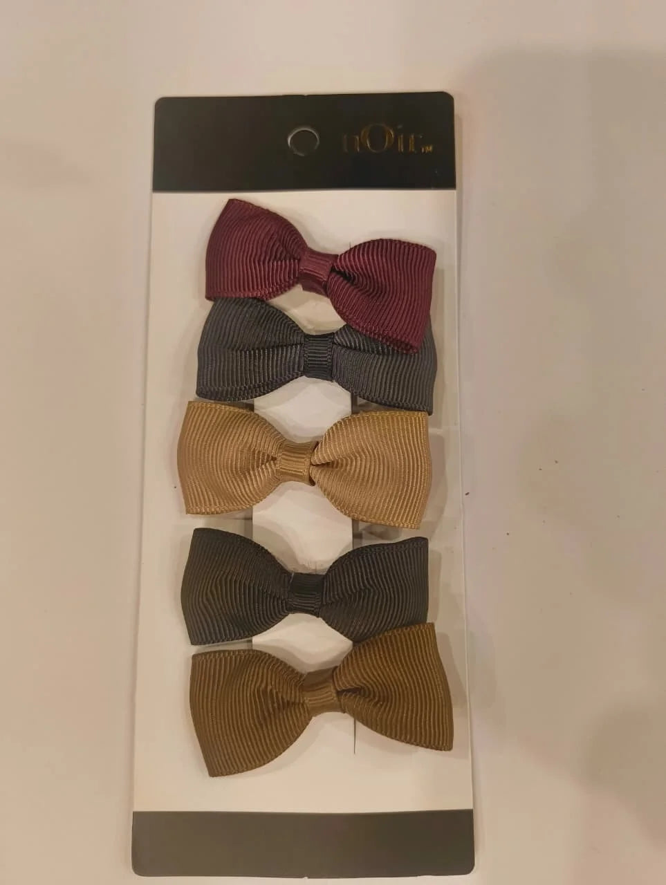 Set of five bow ties in different colors on a white card with a brand name.