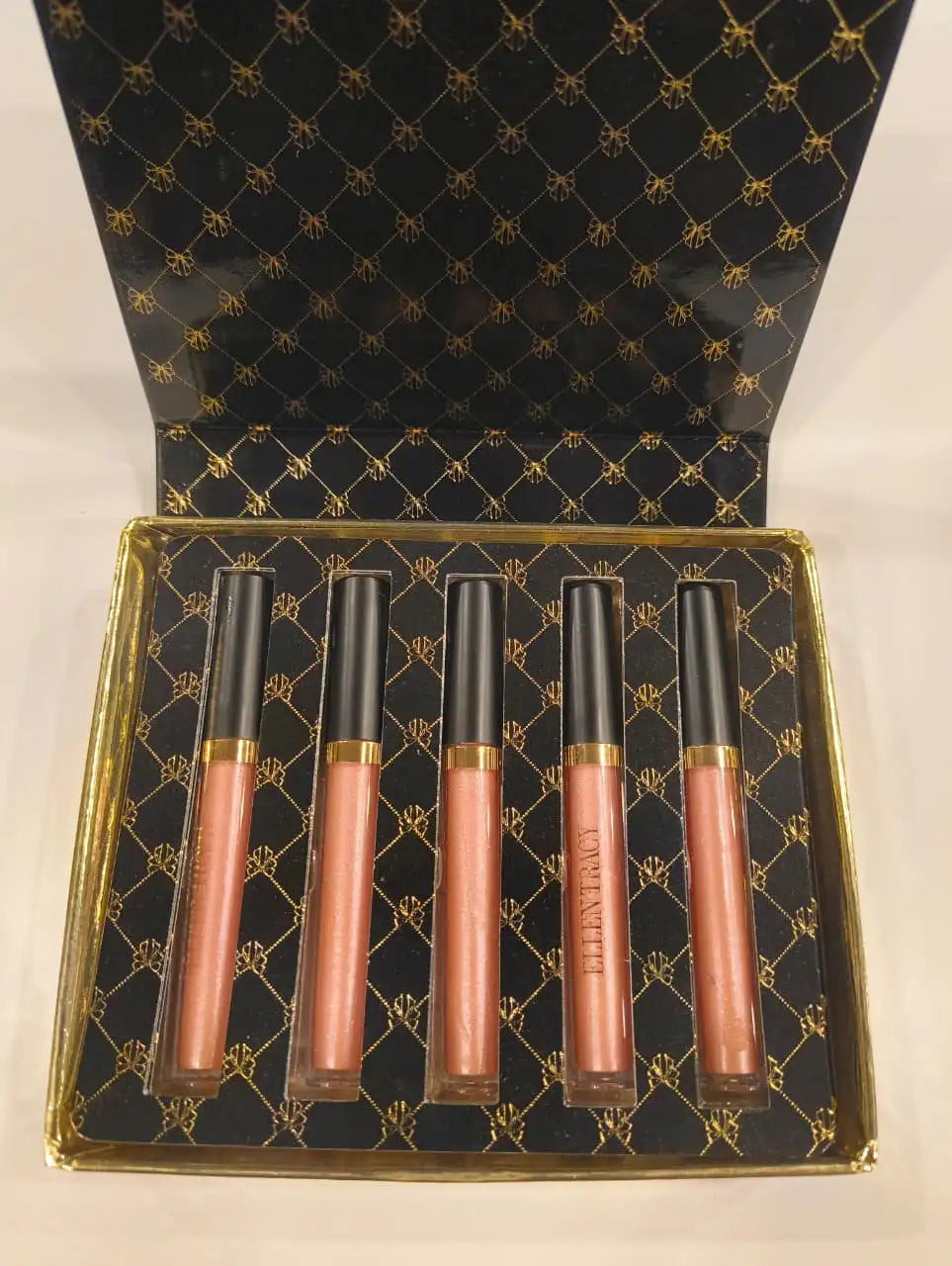 Set of five lip glosses in a decorative box with a black and gold pattern.